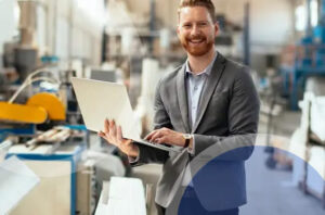 businessman on factory floor with laptop computer