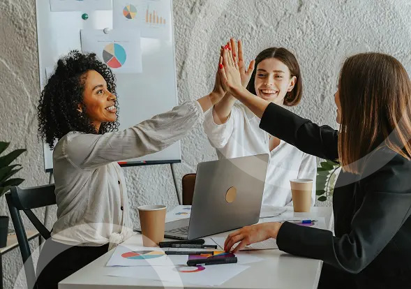 women high fiving over a laptop computer