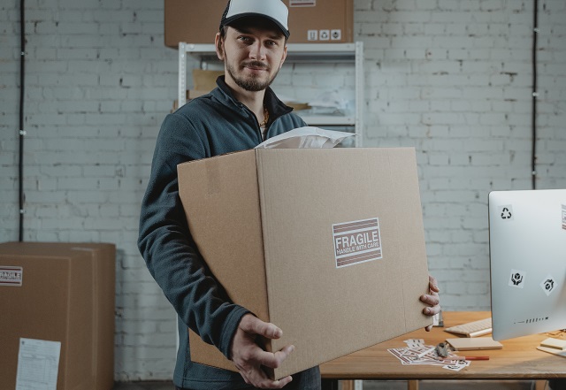man with hat carrying box