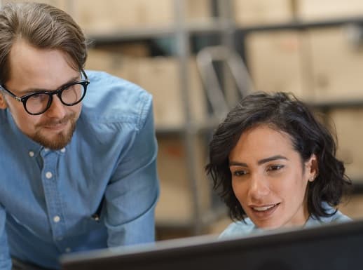 Male and female coworkers looking at computer monitor