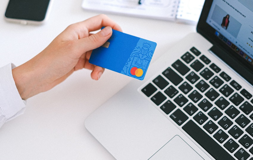 female hand holding credit card over laptop