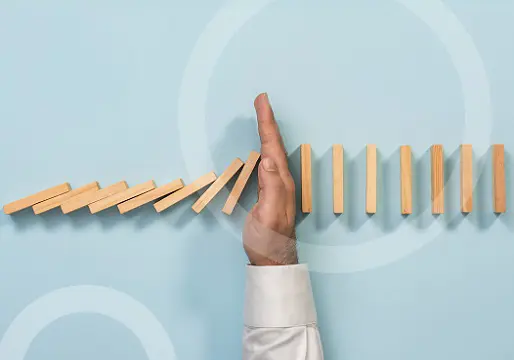 man's hand stopping domino cascade