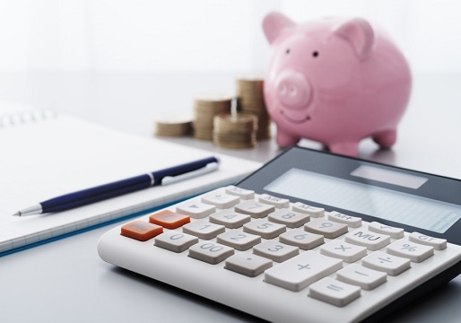 piggy bank next to calculaor and pen
