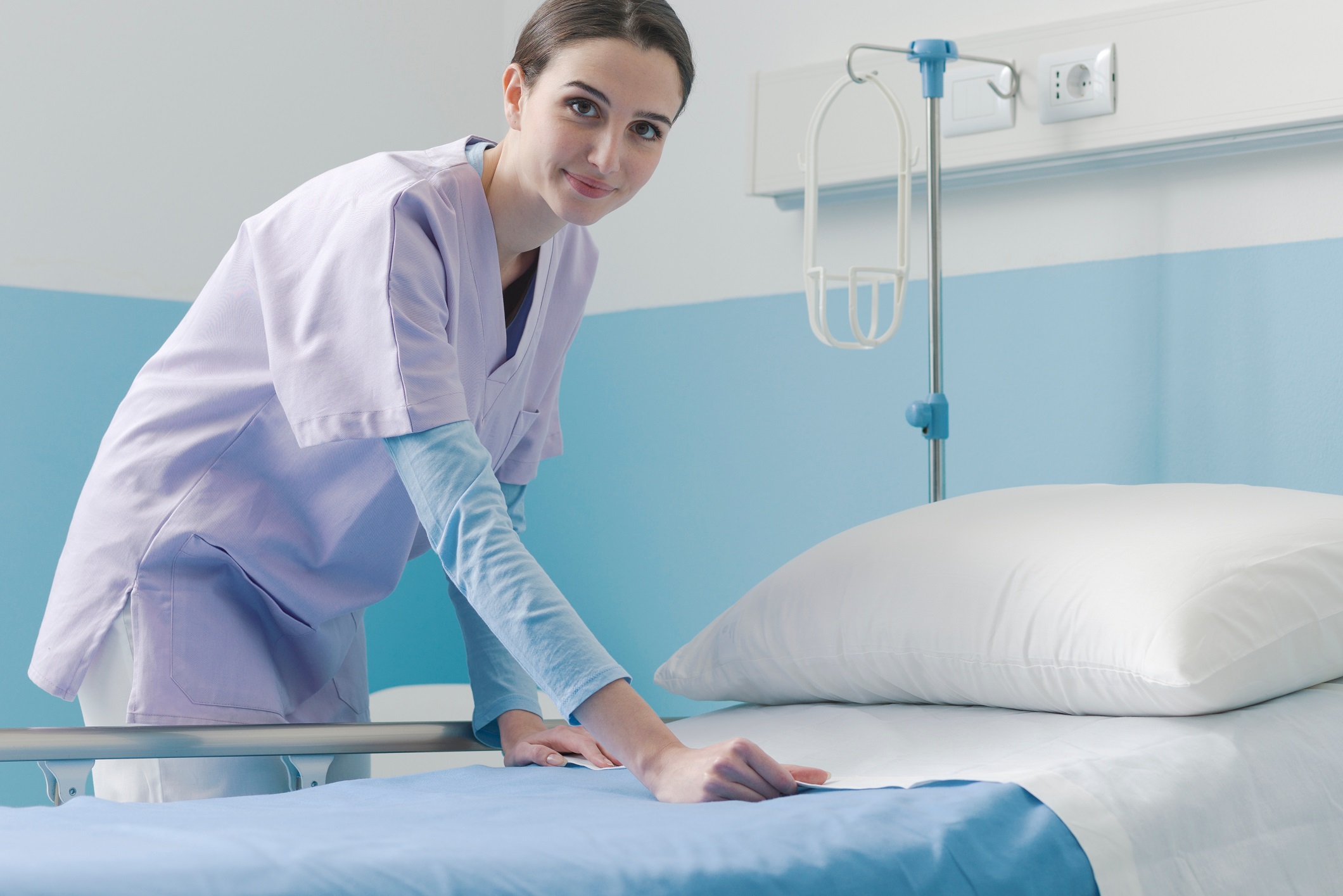 nurse smiling while making hospital bed