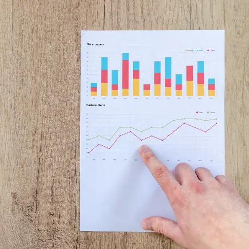 person pointing paper line graph