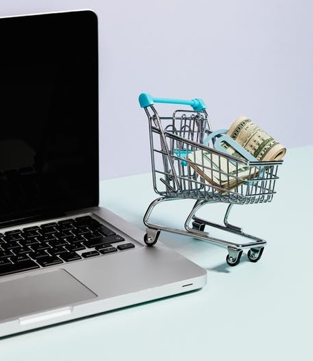 shopping cart with money clip, next to laptop