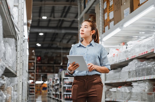 woman with tablet walking down warehouse aisle