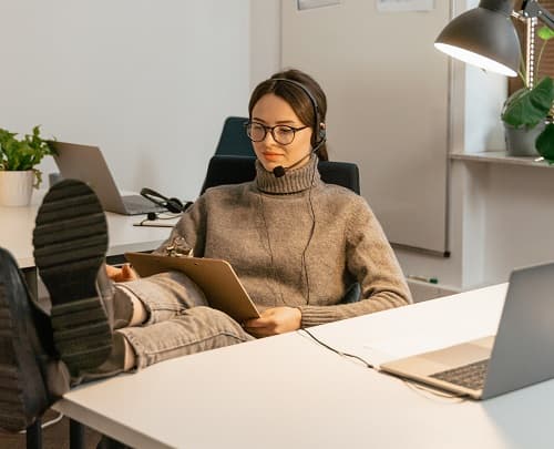 woman in sweater with feet up on office desk