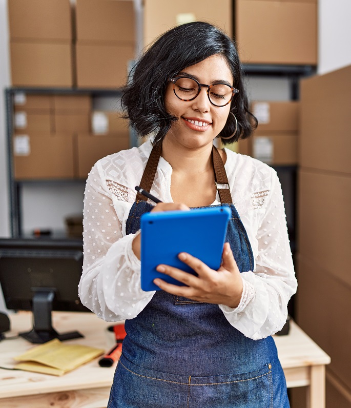 woman in apron holding blue tablet