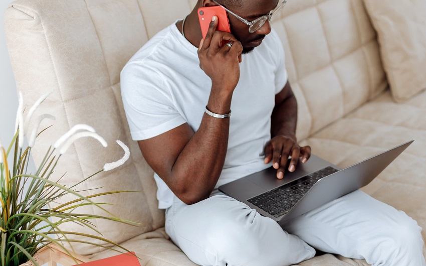 man on couch with laptop and smartphone